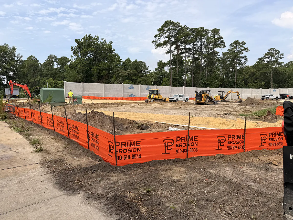 Printed Prime Erosion silt fence running along a precast concrete sound wall