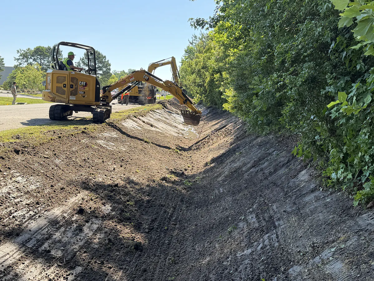Excavator cutting a roadside drainage ditch to grade